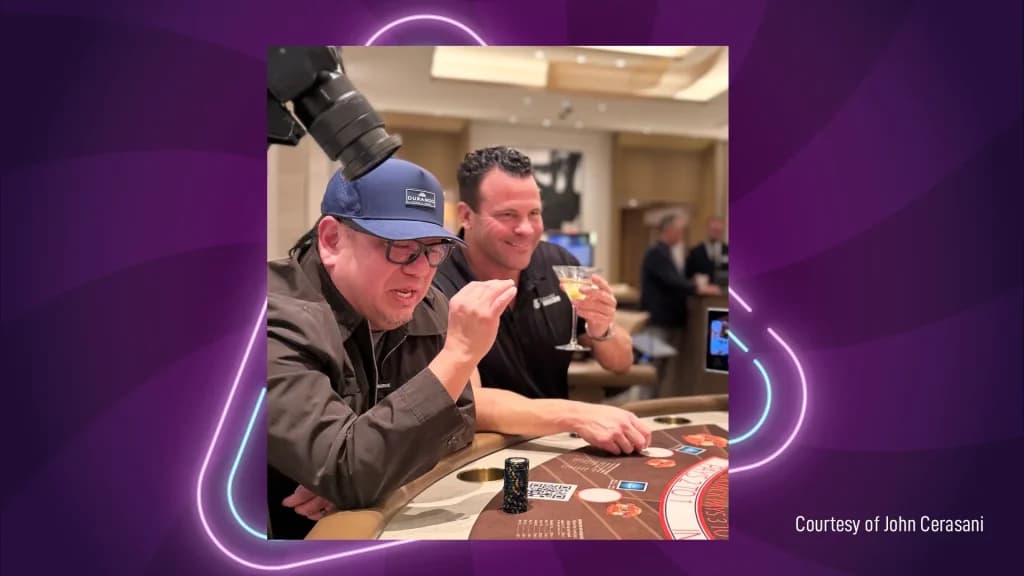John Cerasani at a casino blackjack table, smiling with a drink in hand alongside a friend.