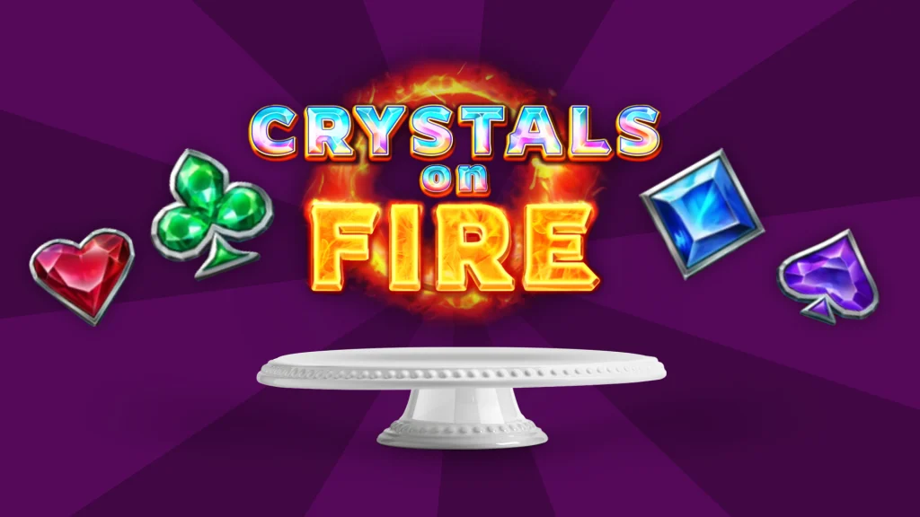 On top of a cake tray are the words ‘Crystals on Fire’ with a ring of fire behind them. Playing card symbols are on either side, and it’s all over a dark purple background. 