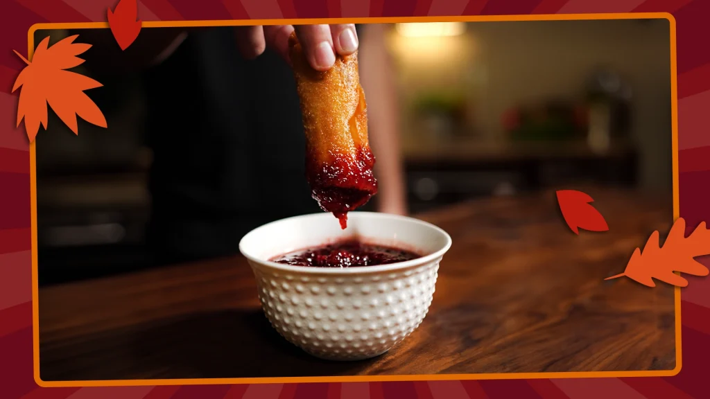 fried egg roll dipped into bowl of cranberry sauce 