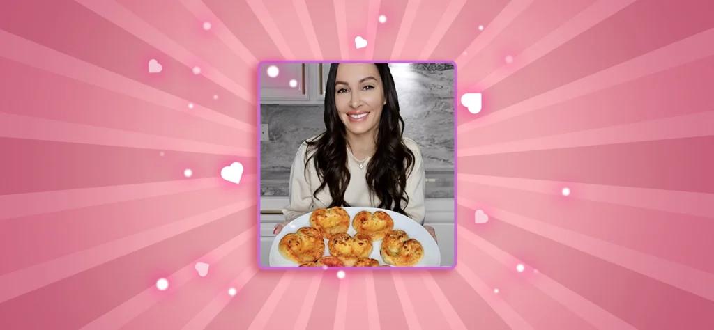 Chef Gen carries a plate of mini heart shaped pizzas on a pink background