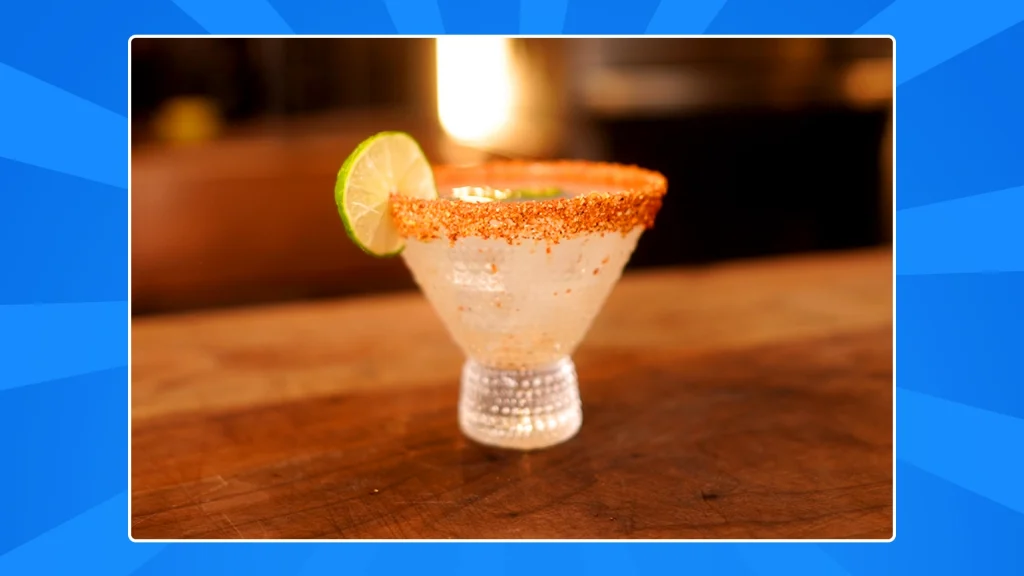 A spicy margartita with a lime wheel on a blue background