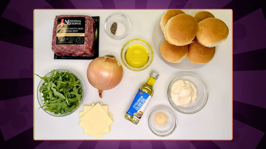 Ingredients laid out: wagyu ground beef, salt, black pepper, brioche slider buns, slices of white cheddar cheese, Arugula, onion, olive oil